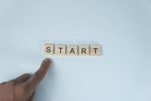 Hand Pointing at Wooden Tiles Spelling START on White Background Motivation and New Beginning photo