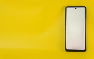 Smartphone with a blank screen against a horizontal yellow background photo
