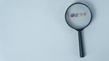 Letter Beads Spelling Find Inside Magnifying Glass on white Background photo