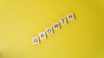 Wooden Letters Spelling GRsOWTH Diagonally on Yellow Background Personal Development and Progres photo