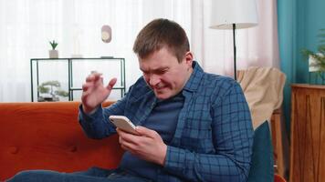 Sad displeased man using smartphone browsing loses surprised game results bad news fail app virus video