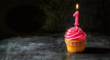 Cupcake with pink candle on top of table photo