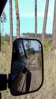 Off-road vehicle driving through forest path, rearview mirror reflection of dirt trail in pine woodland photo