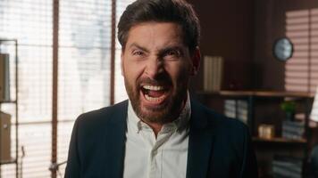 Angry furious mad stressed European business man in office yelling screaming shouting looking at camera yell anger rage emotion overworked problem scream male employer guy entrepreneur businessman photo