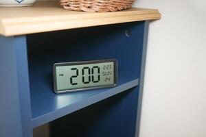 Digital clock displaying time and temperature on a shelf photo