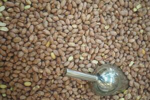 Raw peanuts spread out with a silver scoop for easy serving photo