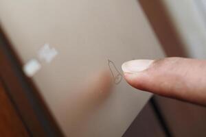 Finger tracing a simple drawing on a frosted glass surface photo