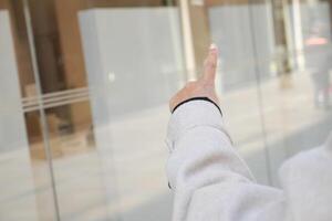 Person pointing at a transparent window in an urban setting photo