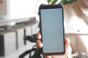 Holding a smartphone in a bright indoor setting near plants photo