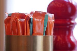 Colorful sugar packets in a container at a cafe table photo