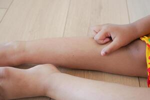 Close-up of child's leg with hand touching skin while relaxing indoors photo