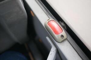 Red emergency button next to bus window during daytime travel photo