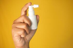 A hand holds a small ear spray bottle with a pump nozzle in focus photo
