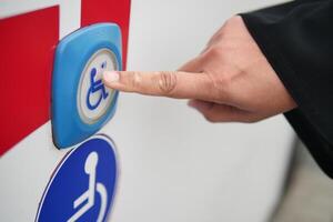Hand pressing accessibility button on vehicle for assistance photo