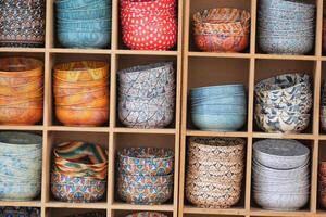 Unique ceramic bowls displayed in organized wooden shelving photo