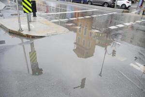 Reflections of a building in a rainwater puddle on the street photo