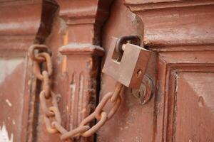 Locked wooden door with a chain and padlock in a rustic setting photo