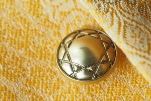 Decorative golden button with intricate design on vibrant fabric photo