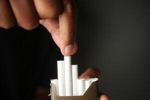 Person placing white tubes into a container in a dimly lit setting photo