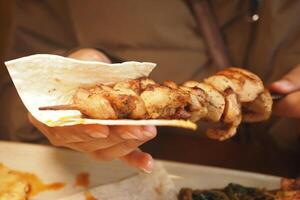 Grilled chicken skewer being served with flatbread at local eatery photo