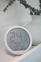Digital thermometer displaying temperature and humidity indoors photo