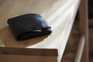 Wallet resting on a wooden table in warm natural light, lost wallet concept photo