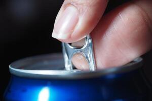 Opening a soda can with a finger in close-up view photo