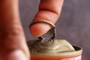 Opening a beverage can with a metal tab using a finger photo