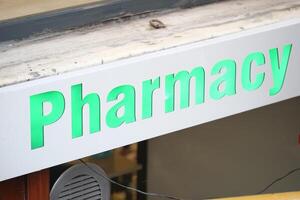 Pharmacy sign illuminated in vibrant green at a city location photo