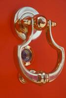 Door knocker on a vibrant red wall at a charming entrance photo