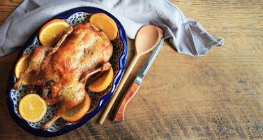 Whole crispy golden roast duck with marinated with fresh orange slices for a festive Top view rustic wooden background. photo