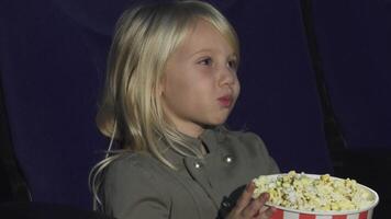 Adorable little girl enjoying popcorn at the cinema video