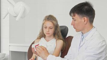 Young girl joyfully learning to brush teeth with a dentist using a dental model video
