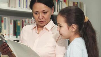 Joyful mother and daughter exploring books together in a cozy library video