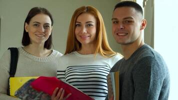 Three students smiling together in a college lecture hall video