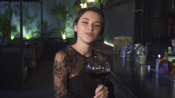 Charming young woman at the bar, smiling brightly with a glass of red wine video