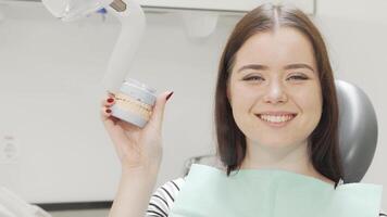 Cheerful woman smiling while holding a dental teeth model video