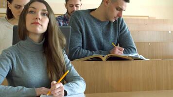 Focused students diligently writing in their exercise books during a lecture video