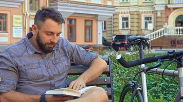 Cyclist engrossed in reading a book while resting on a bench video