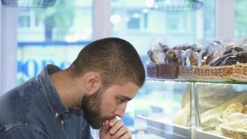 Thoughtful man savoring dessert choices at a charming bakery showcase video
