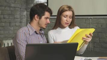 Dynamic business duo collaborating on a project with a laptop in a modern office video