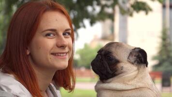 Girl playfully trying to kiss her adorable pug while smiling at the camera video