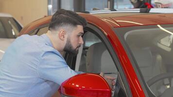 Smiling man examining a sleek new car at the dealership video
