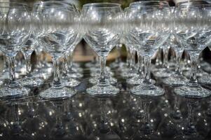 Many empty clean wine glasses on dark background in daylight. wine glasses, bar, glass, rows, empty glass, transparent, glass, many. Wine glasses on black background close-up photo