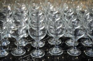 Many empty clean wine glasses on dark background in daylight. wine glasses, bar, glass, rows, empty glass, brown, transparent, glass, empty, many. Wine glasses on black background close-up. photo