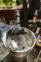Odessa, Ukraine - April 05, 2025. A bottle of champange in an ice bucket at a hotel outdoors on a spring day. In the background, a bottle of wine and glasses. The blurred background includes a wine glass photo