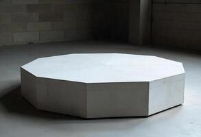 A white dodecagon platform in a room with concrete walls and floor, the background is dark photo
