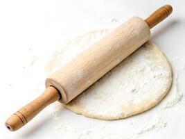 A wooden rolling pin on a dough with flour on a white surface photo