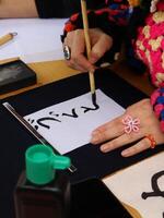 Person practicing calligraphy with brush and ink. Close-up of a person's hand delicately applying ink with a brush to a sheet of paper, practicing Chinese Calligraphy photo