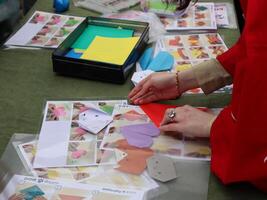 Hands Folding Origami Figures at a Workshop. Close-up of hands carefully folding origami, likely at a community workshop or craft fair. photo